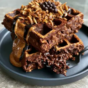 Close-up of chocolate almond oat waffles showing the brownie-like texture and toasted almond toppings.